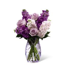 Purple and lavender flowers arranged in a clear vase