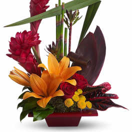Tropical arrangement with red ginger, orange lilies, red roses, and yellow button flowers in a red container