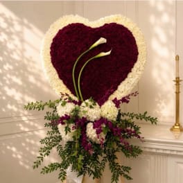 Heart-shaped floral arrangement with two white calla lilies and purple and white flowers