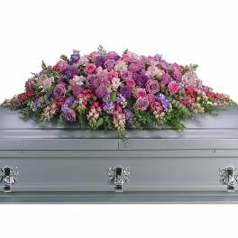 Long spray of pink and purple flowers arranged on top of a silver casket