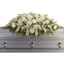 White casket spray of chrysanthemums and mixed white flowers on a silver casket.