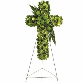 All-green floral cross arrangement displayed on a tall metal easel stand.