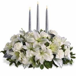 Low white lily and carnation centerpiece with three silver taper candles