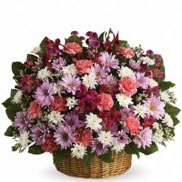 Low basket of pink carnations, white and lavender daisies, and dark pink blooms in a rounded arrangement.