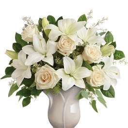 Arrangement of white lilies and cream roses in a pale ceramic vase