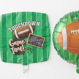 Two green football-themed foil balloons on a white background.