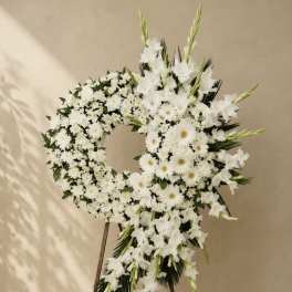 White floral funeral wreath on a stand with daisies and lilies