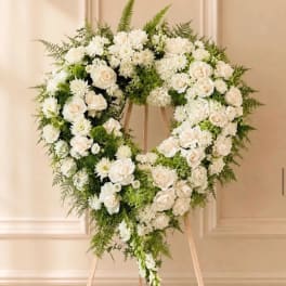 Heart-shaped white floral wreath on a wooden stand