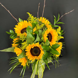 Sunflower bouquet in a glass vase with yellow filler flowers