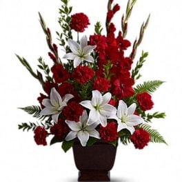 Red carnations and white lilies in a dark urn vase