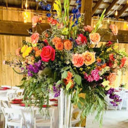 Tall colorful floral centerpiece in a clear vase on a reserved table