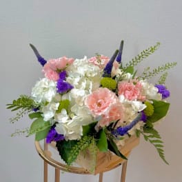 Pink and white floral arrangement in a wooden box with purple accents