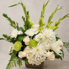 White and green floral arrangement in a brown container