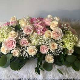 Low arrangement of pink and cream roses with hydrangeas and baby's breath