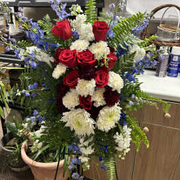 Standing floral spray with red roses, white carnations, and blue delphinium