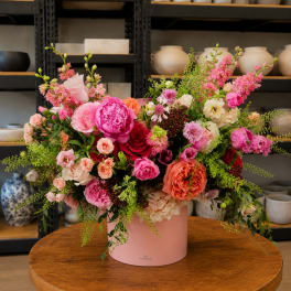 Pink and coral mixed flower arrangement in a pink hat box