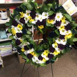 Heart-shaped floral wreath with white, yellow, and dark purple flowers
