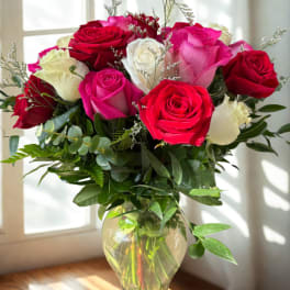 Bouquet of red, pink, and white roses in a clear glass vase