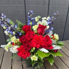 Red roses and carnations with blue delphinium in a glass vase