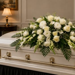 White floral spray on a casket with roses and calla lilies