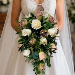 Bride holding a cascading bouquet of cream and blush roses
