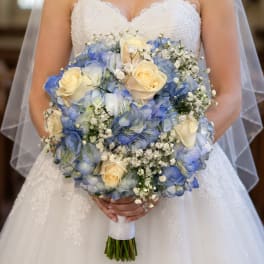 Bride holding a bouquet of blue hydrangeas and cream roses
