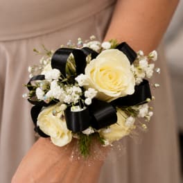 Small wrist corsage with cream roses, baby's breath, and black ribbon