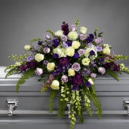 Purple and white floral casket spray with cascading blooms