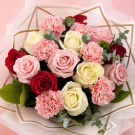 Bouquet of pink, red, and cream roses with pink carnations