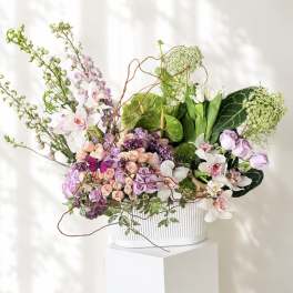 Mixed pastel floral arrangement in a white ribbed container
