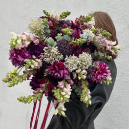 Large bouquet of purple, pink, and white flowers held by a person