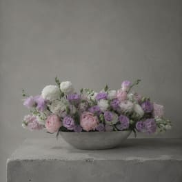 Low pastel flower arrangement in a shallow gray bowl