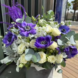Purple anemones and white roses in a vase with eucalyptus
