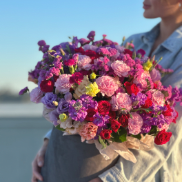 Person holding a large bouquet of pink, purple, and red flowers