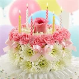 Pink and white flower arrangement topped with candles and balloons