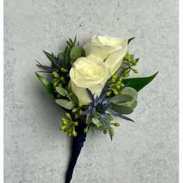 White rose boutonniere with blue-green foliage on a dark wrap