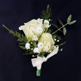 White rose boutonniere with small white filler flowers and a ribbon tie