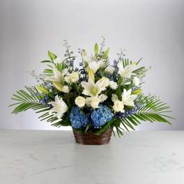 White lilies and blue hydrangeas in a woven basket