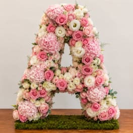 Pink and white floral letter A arrangement on a moss base