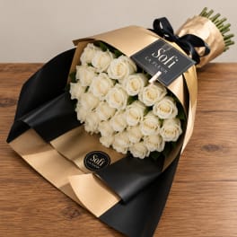 Bouquet of white roses wrapped in gold and black paper with a ribbon