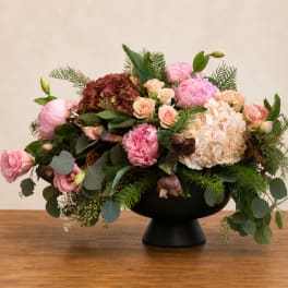 Pink and cream floral arrangement in a black pedestal vase