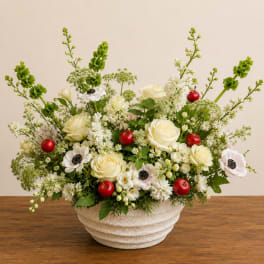 Cream roses and white anemones in a textured white bowl with red berries