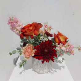 Mixed bouquet with orange roses and red chrysanthemums in a white vase