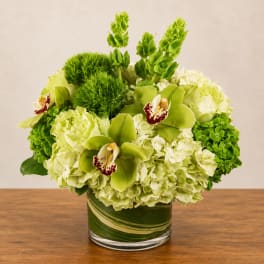 Green and white floral arrangement in a glass vase