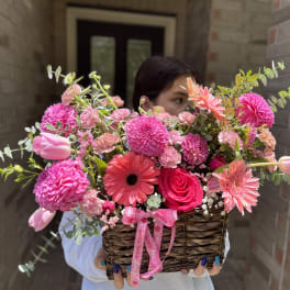 Basket of pink flowers with tulips, roses, and daisies
