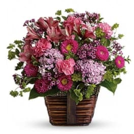 Pink and purple mixed flower arrangement in a woven basket
