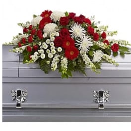 Red and white funeral spray on a gray casket