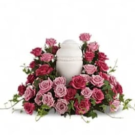 Pink and red roses arranged around a white urn