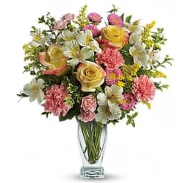 Mixed bouquet of roses, carnations, and white lilies in a clear glass vase