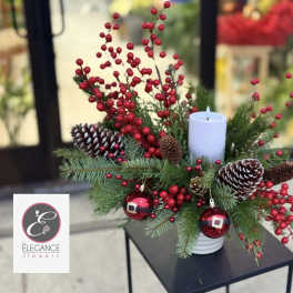 Holiday centerpiece with pine, red berries, pinecones, and a white candle